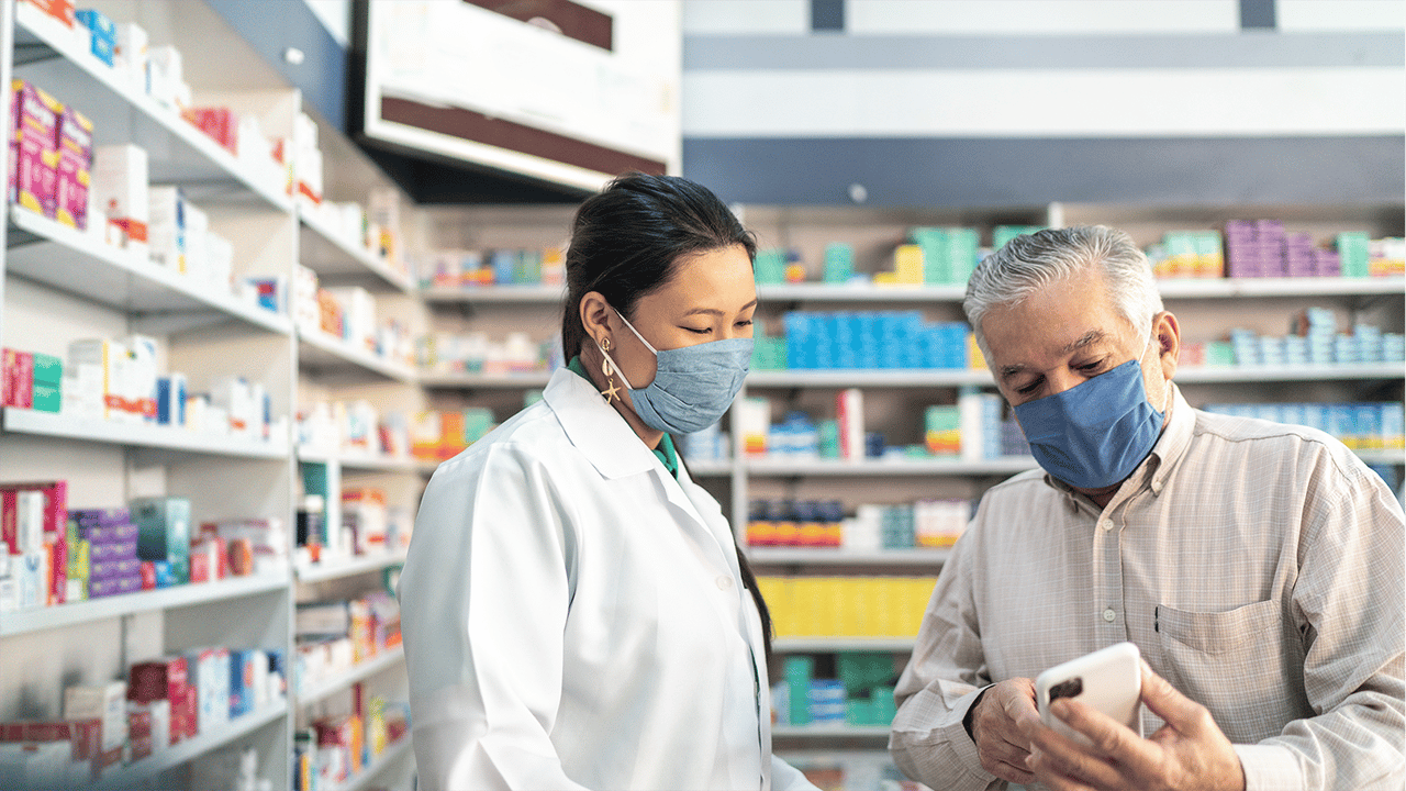 Apothekerin mit Maske hilft Kunden Apothekerin mit Maske hilft einem älteren Kunden am Telefon.