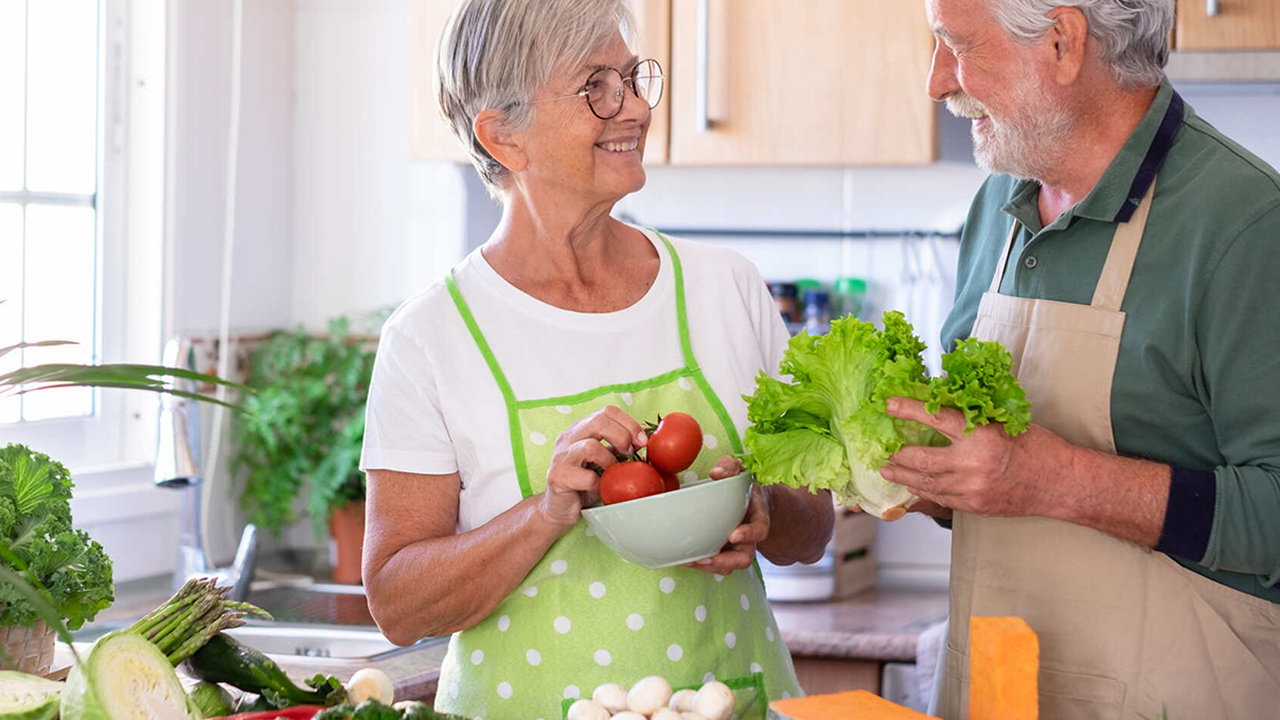 Mann und Frau in der Küche umgeben von frischem Gemüse