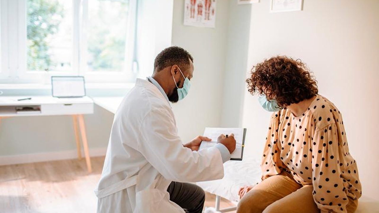 Arzt bespricht etwas mit einer Frau im Behandlungszimmer