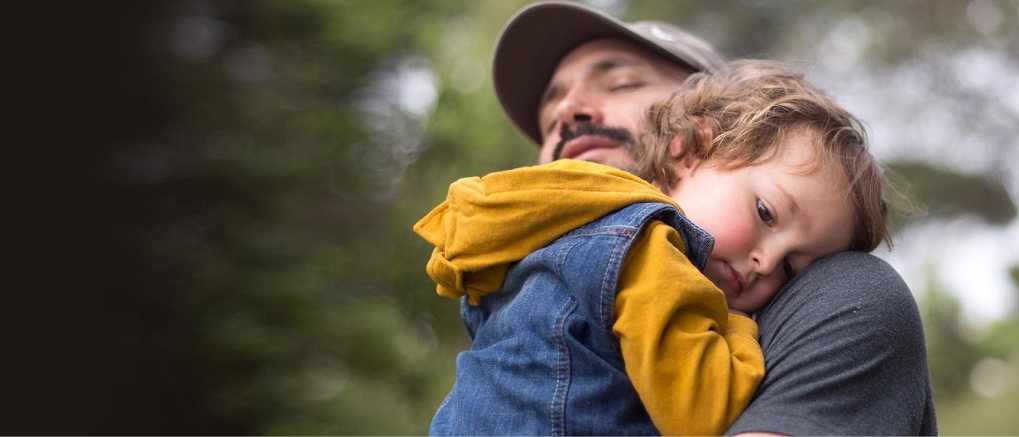 Ein Vater mit Retinitis Pigmentosa hält seinen Sohn auf dem Arm und fragt sich, wie sich die erbliche Netzhauterkrankung auf das Leben seines Sohnes auswirkt