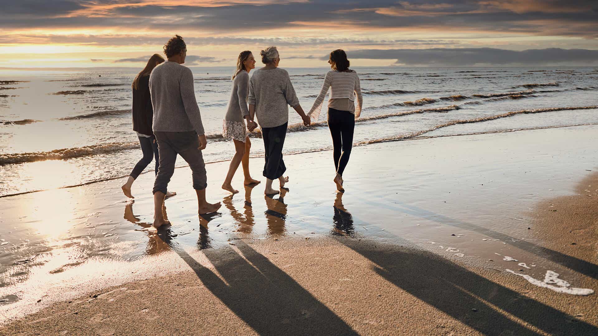 Angehörige und Multiple Sklerose (MS) Patienten spazieren am Strand