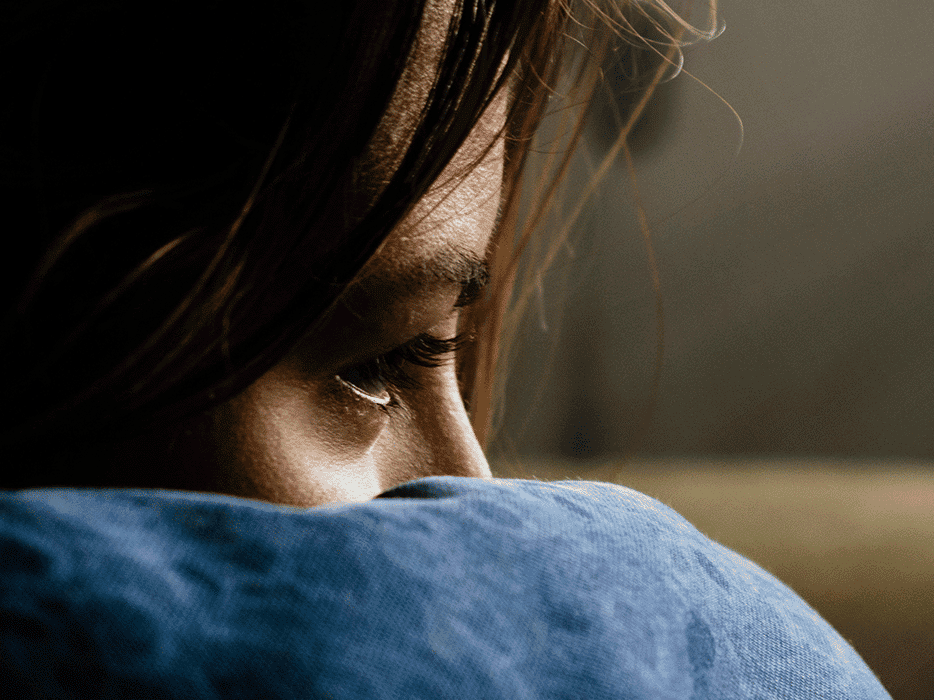 ggd-symptome-header-main Großaufnahme einer Frau, die ihr Gesicht in der Armbeuge vergraben hat. Symbol für depressive Stimmung.