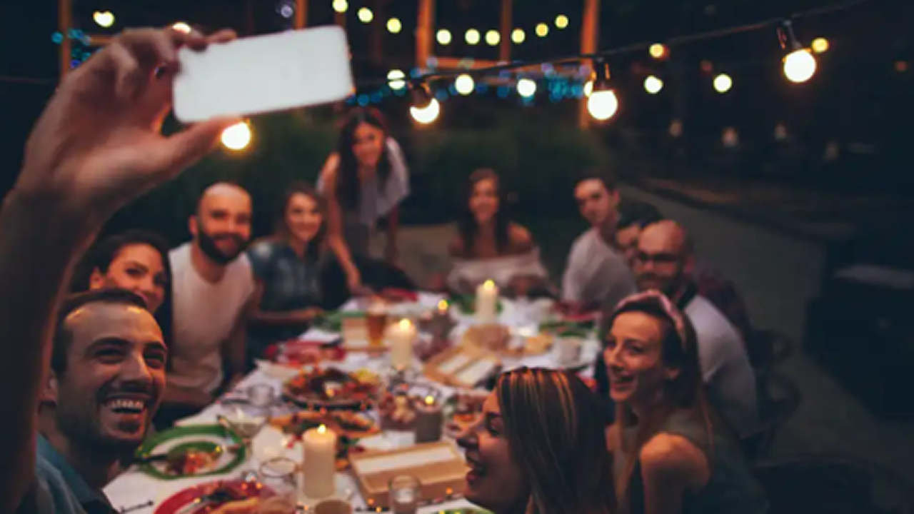 Eine Gruppe sitzt gemeinsam Abends am Tisch im Freien und isst