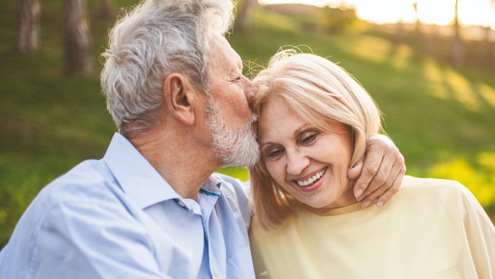 Mann küsst seine Frau auf die Stirn
