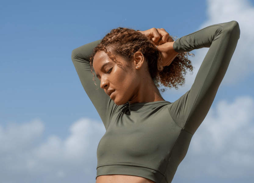 A woman wearing a green sports bra top, getting ready for a workout.