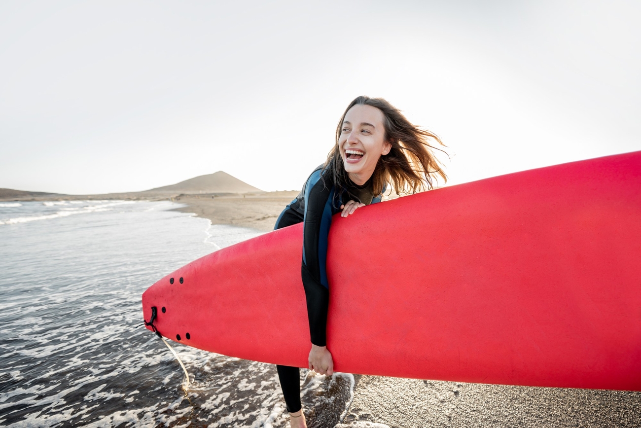 Girl laughing while carrying her red kayak out from the water.