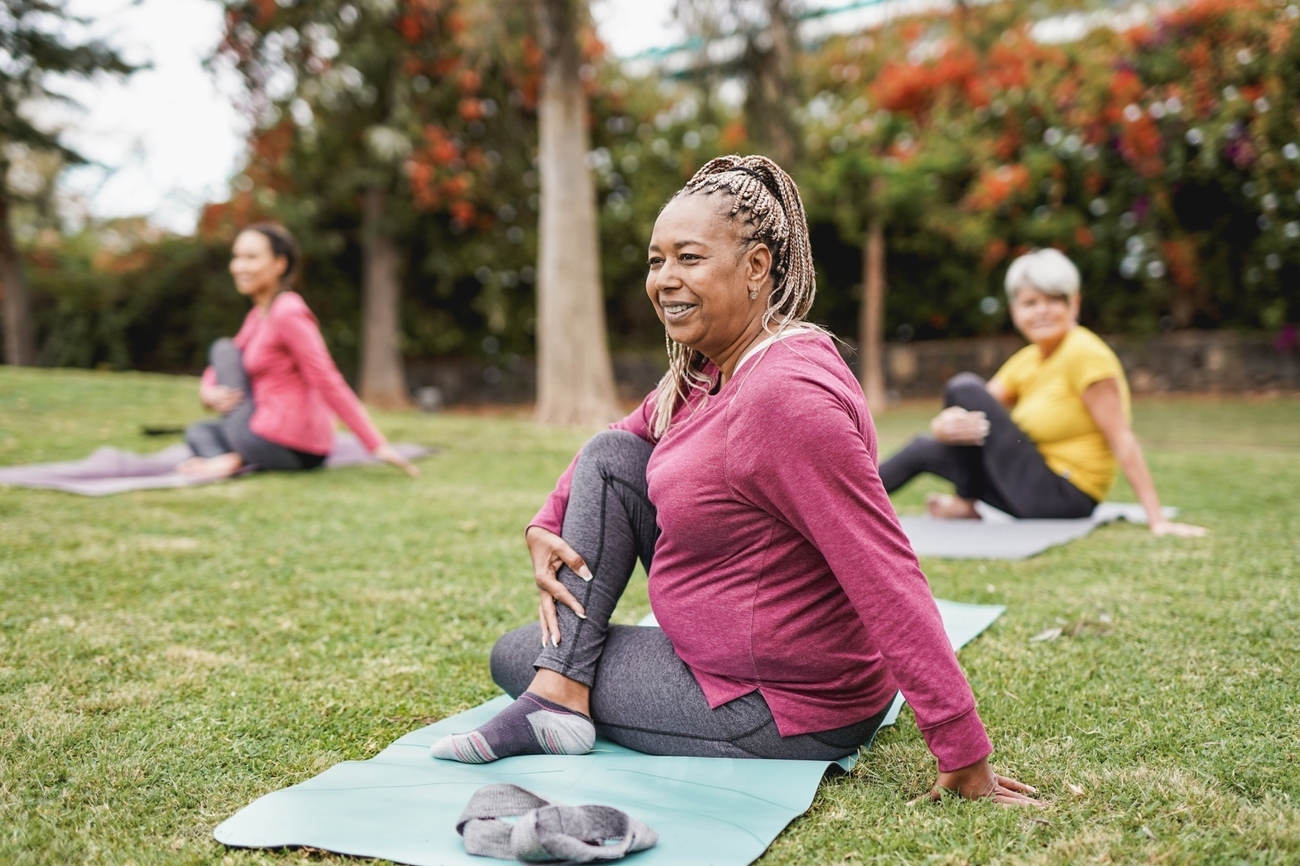 Elderly women practicing yoga outdoors in a park.