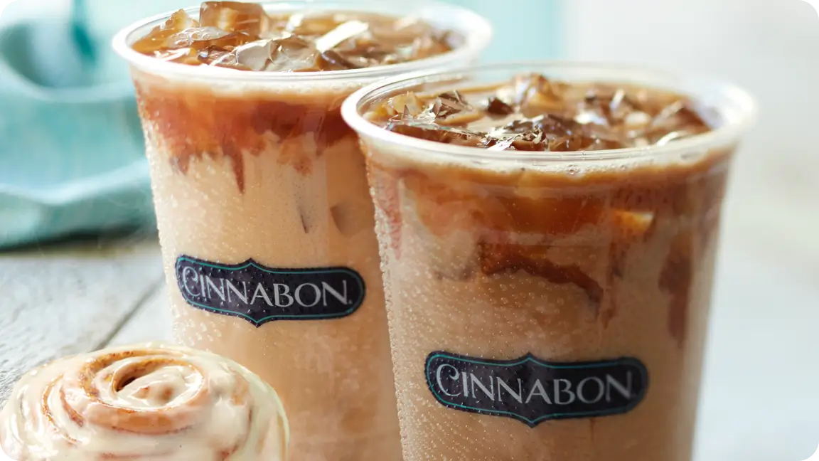 two ice lattes from cinnabon next to 2 iced cinnamon rolls