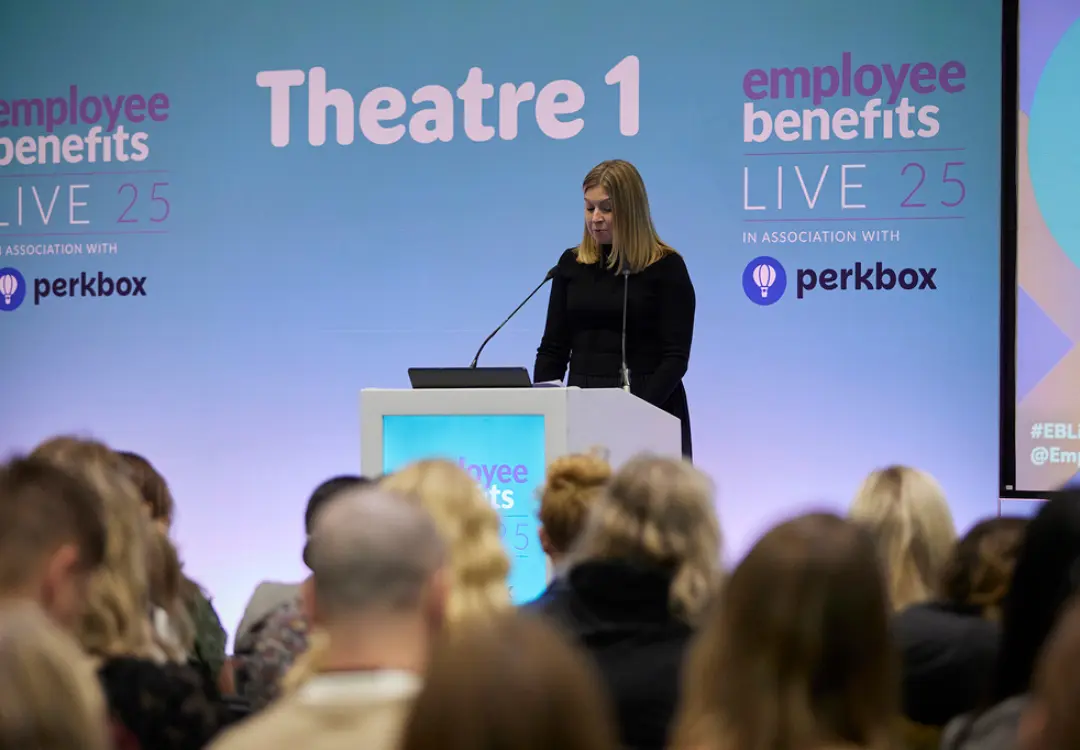 Female speaker at Employee Benefits live event presenting to a crowd of people 
