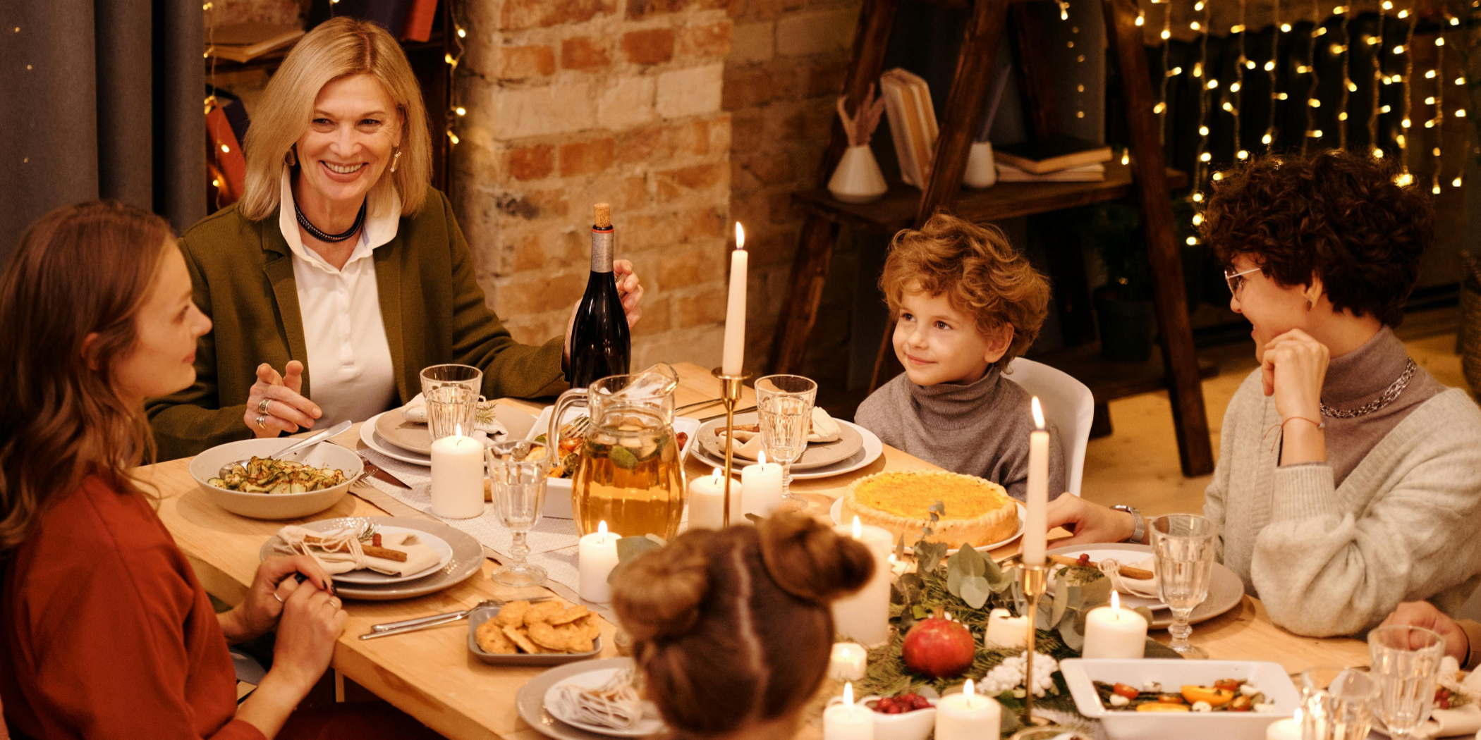 A family enjoying a dinner with candles, fairy lights and wine