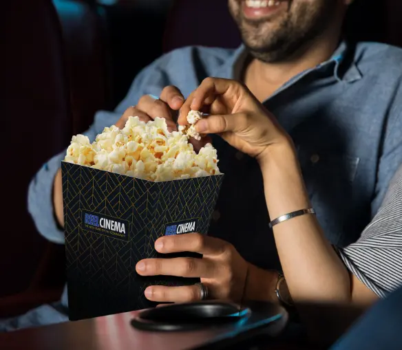 Couple sharing popcorn in the cinema in a branded REEL cinema box