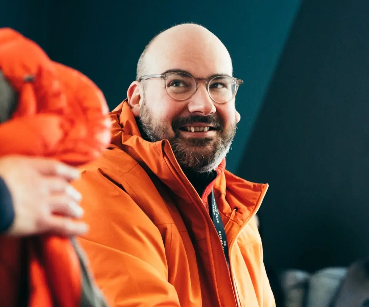 Smiling man in glasses and orange coat