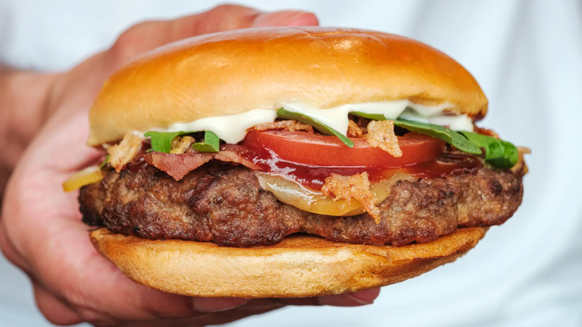 close up of layers of a beef burger including lettuce, tomato, cheese and relish