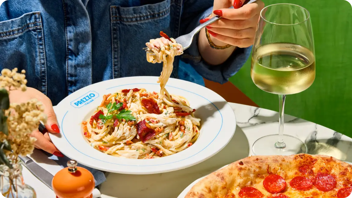 lemon wedge squeezed onto a bowl of spaghetti served with a glass of white wine