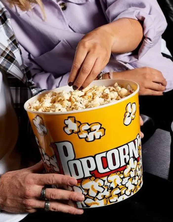 Close up of two people eating from popcorn bucket