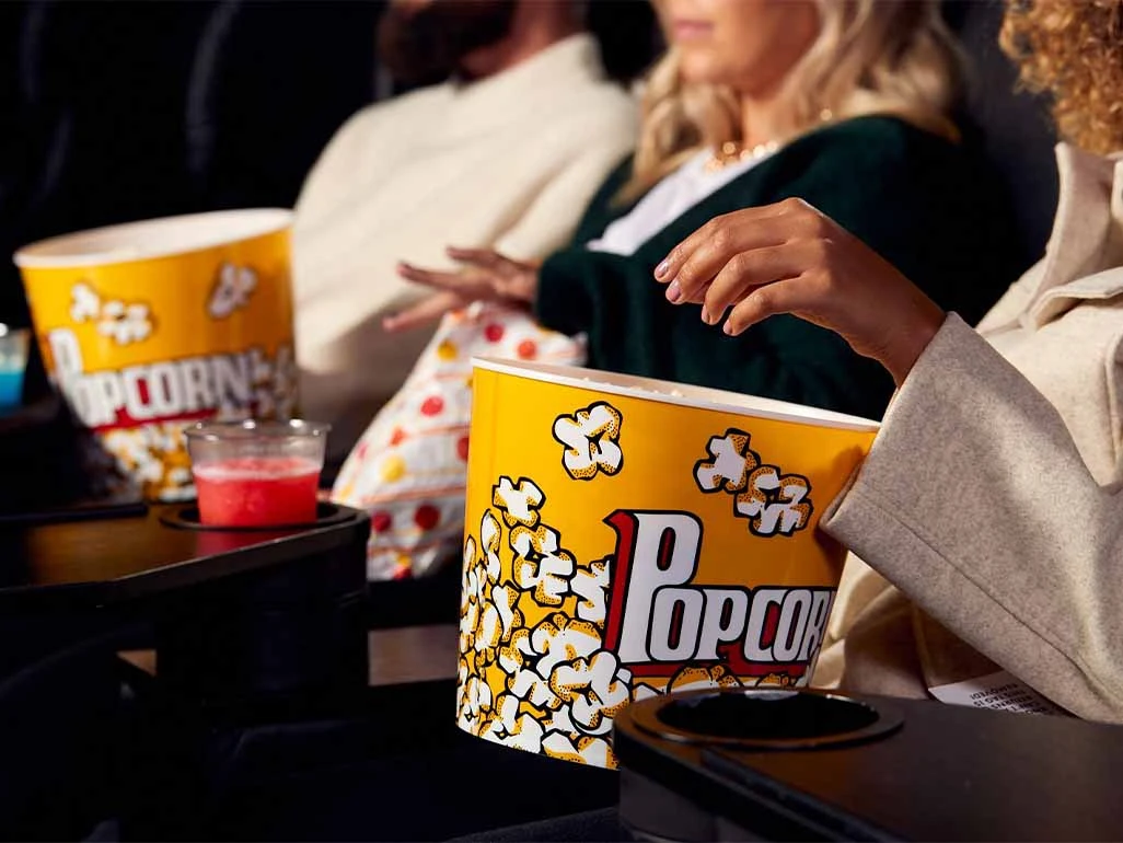 Woman reaching into a tub of popcorn