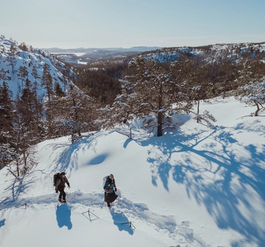 Varg AW25 – två personer vandrar på snötäckt bergsrygg i Varg outdoor-kläder.