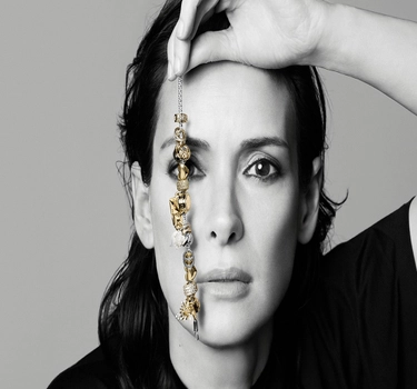 A woman holding a golden Pandora bracelet.