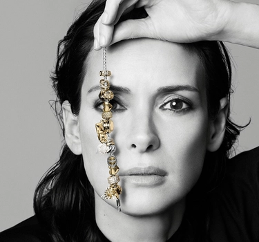 A woman holding a golden Pandora bracelet.