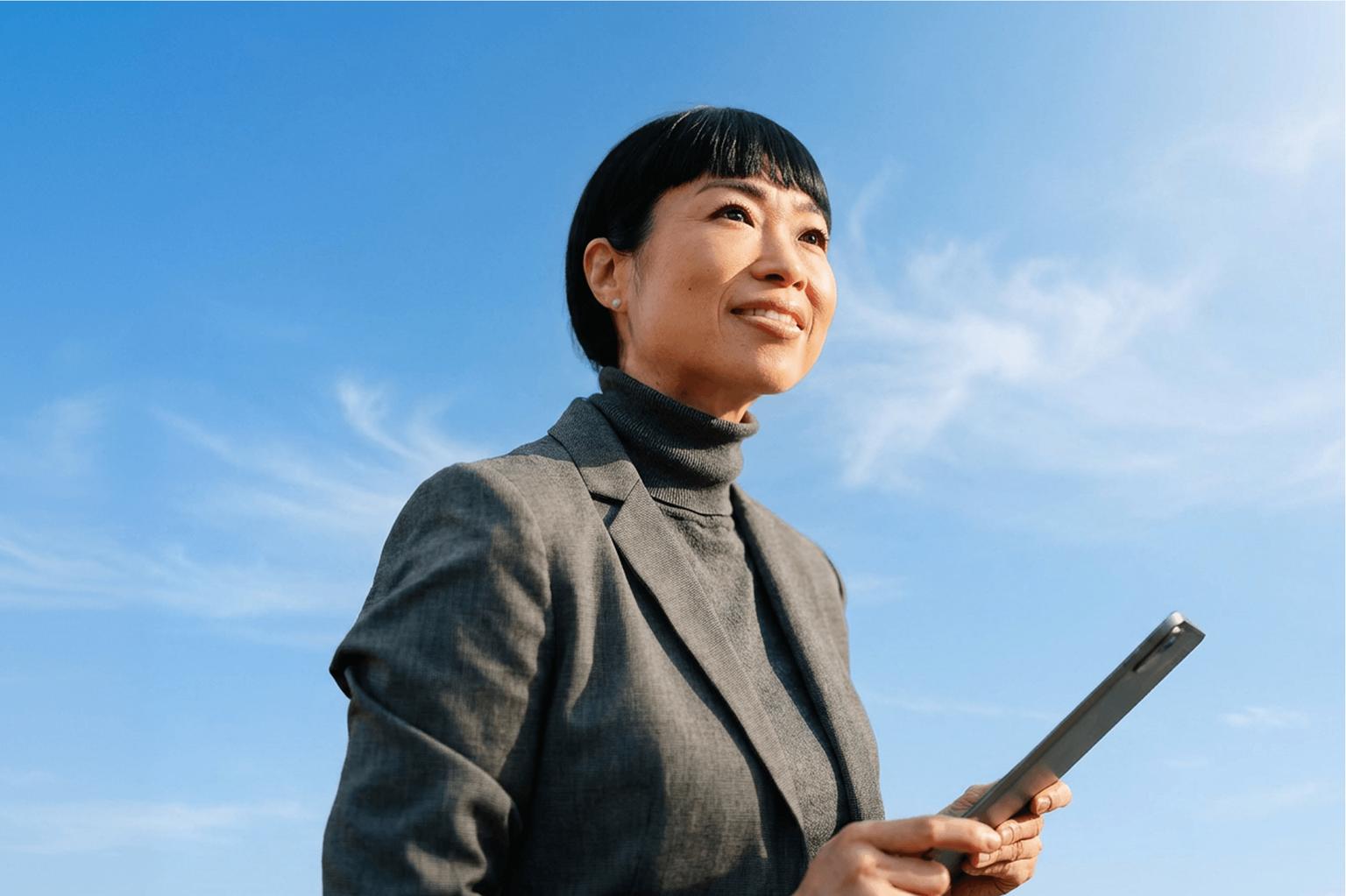 A confident businesswoman looking up against a blue sky