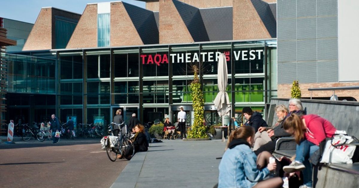 Mensen op bankjes voor Theater De Vest in Alkmaar.