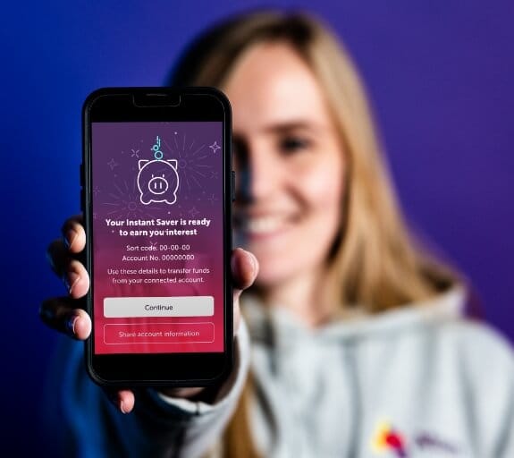 A woman holding a phone displaying the instant saver page for interest