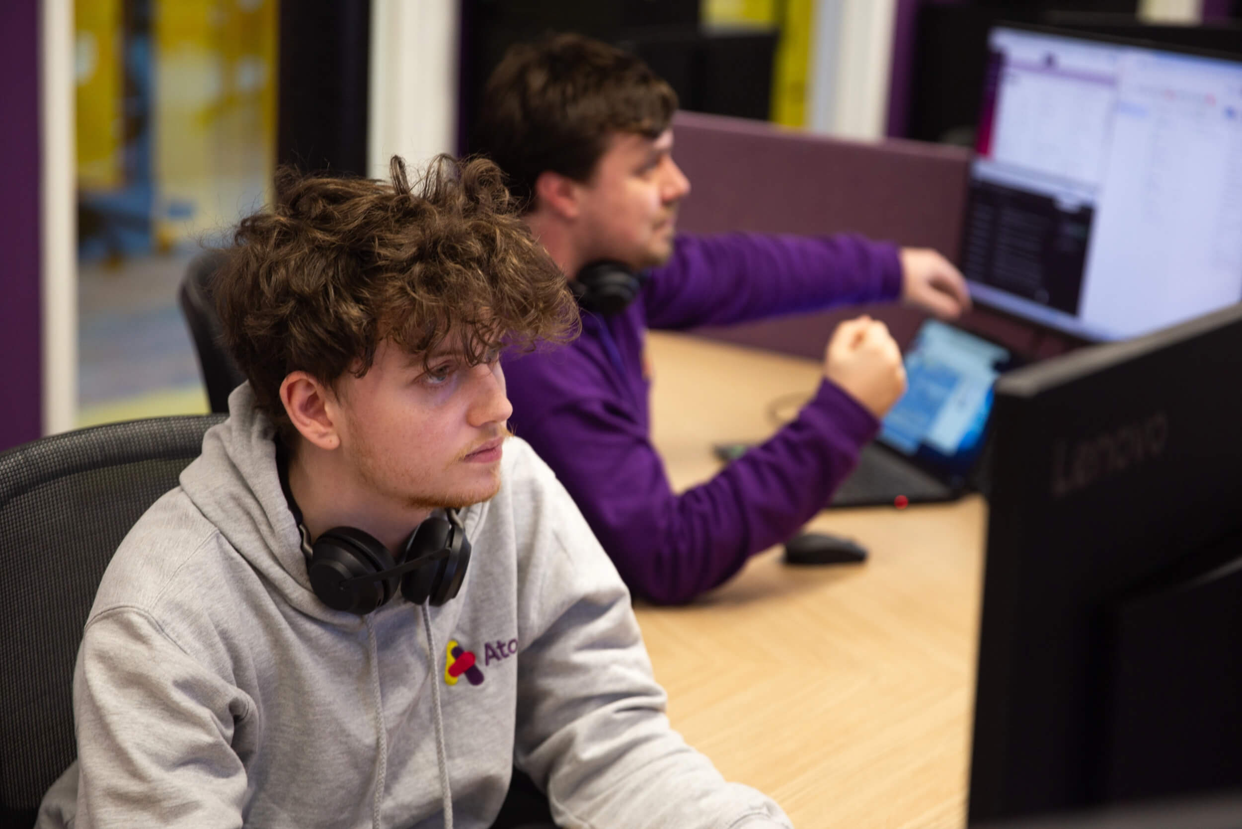 Two men working on computers at their desks