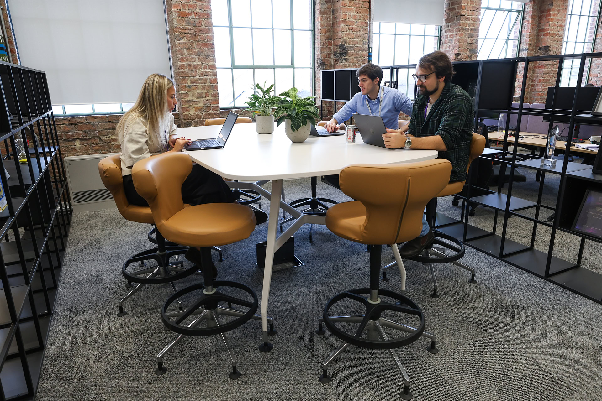 Three people sitting around a table working on their laptops