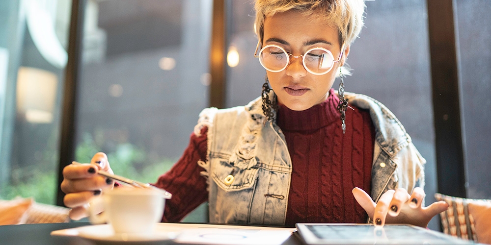 A woman sitting down drinking a coffee whilst working