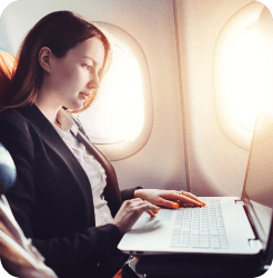 A woman is sat on a plane working on her laptop
