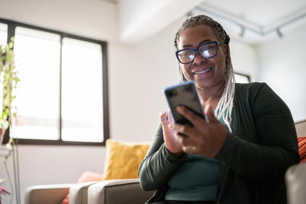 A woman looking at a mobile phone and smiling