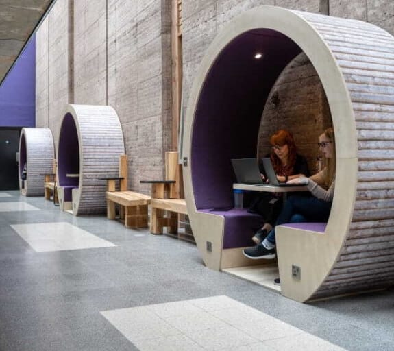 A meeting hub with two people working together on their laptops