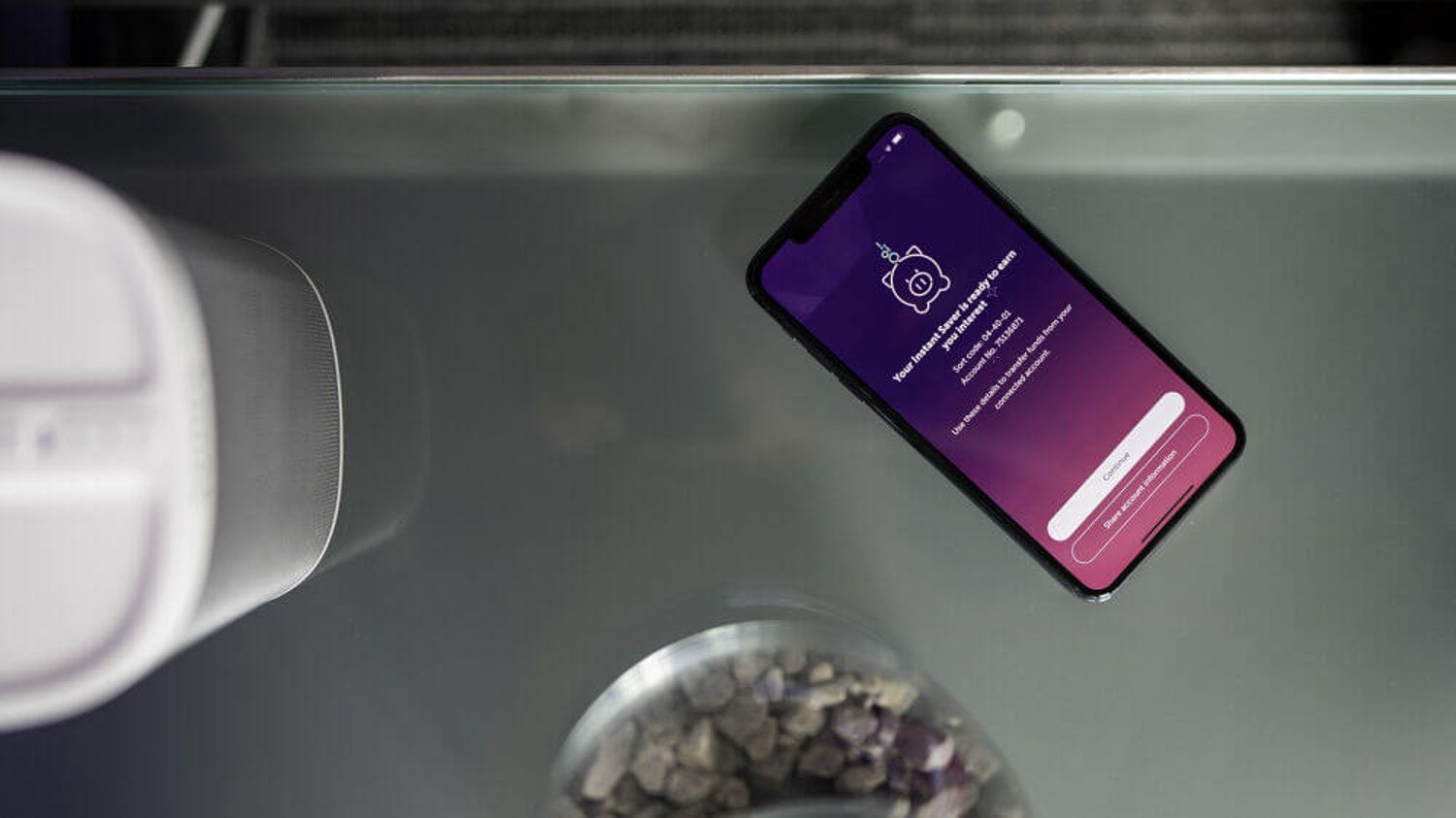 A phone on a table displaying the Atom Bank app