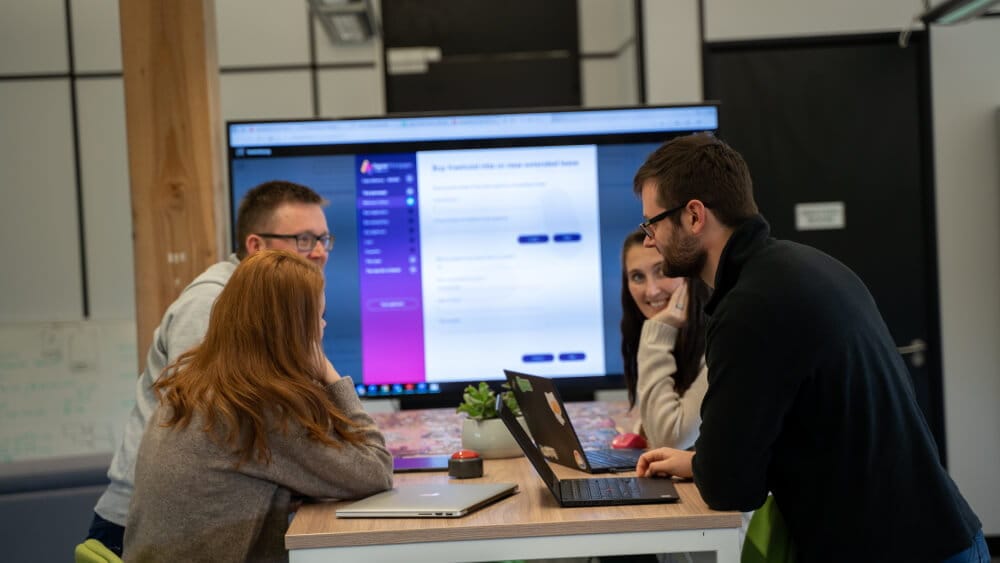 Four people in a meeting room working together