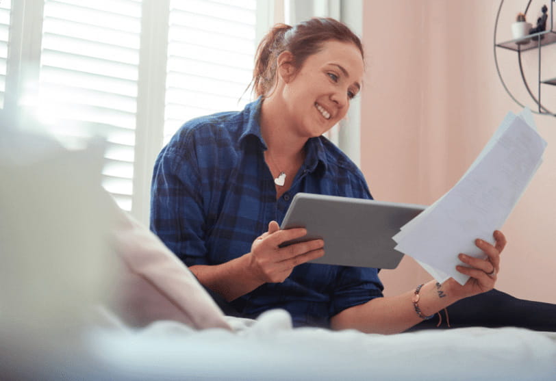 A woman is sitting on her bed reading applications