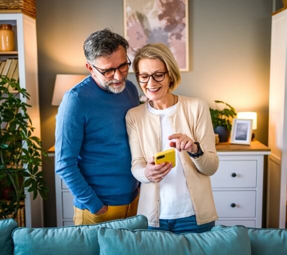 A man and woman smiling and looking at their phone together