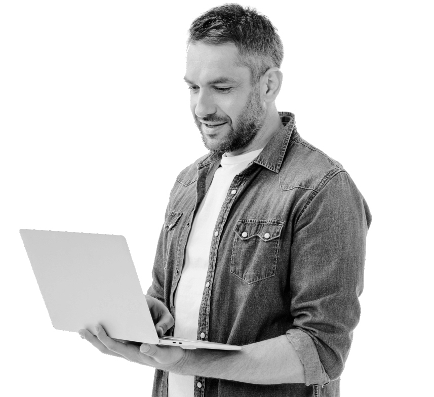 A man is standing and holding his laptop in one hand as he types on the keyboard with the other hand