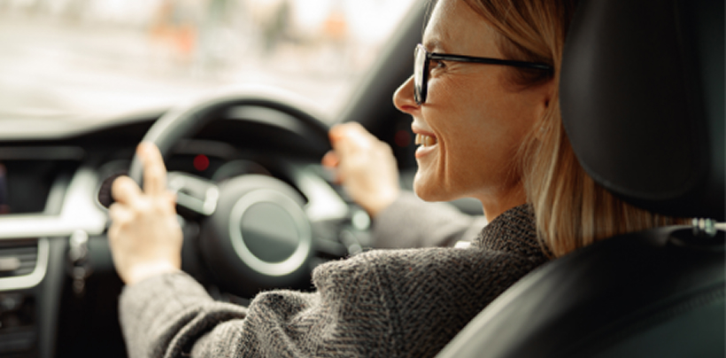 Woman holding a stirring wheel and looking to her left smiling