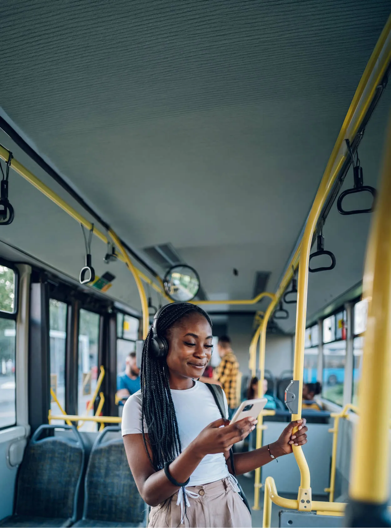 A woman on a bus with headphones on holding a phone