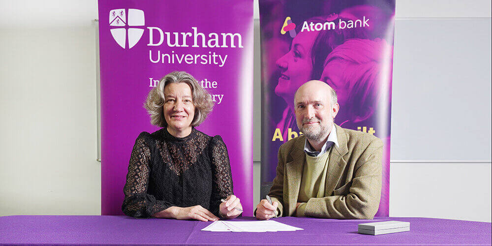 Two people signing an agreement for Durham University