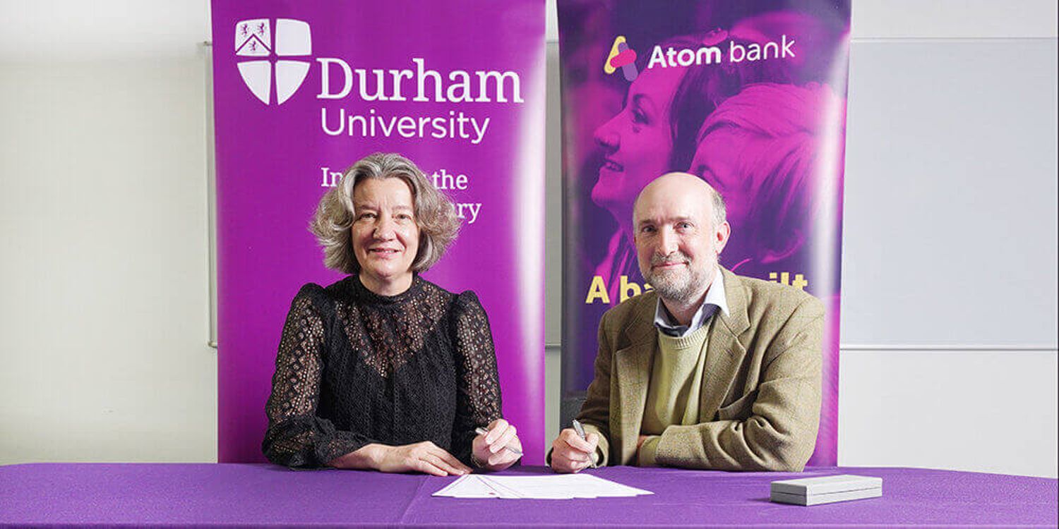 Two people signing an agreement for Durham University