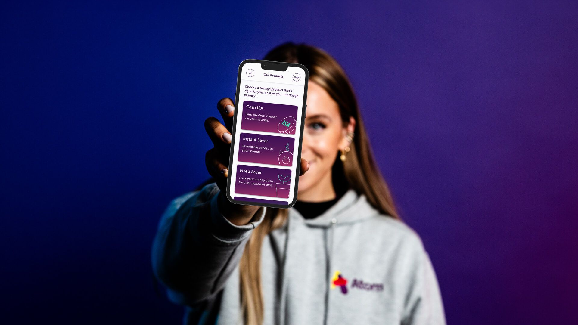 Woman holding a phone out in front displaying the atom bank app products page