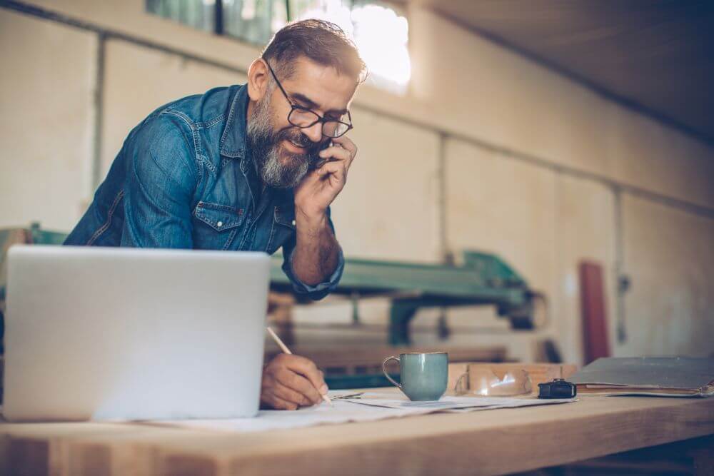 A man on the phone with a pencil in hand writing down some notes