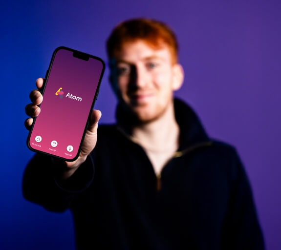 A man holding a phone with the Atom Bank app on display
