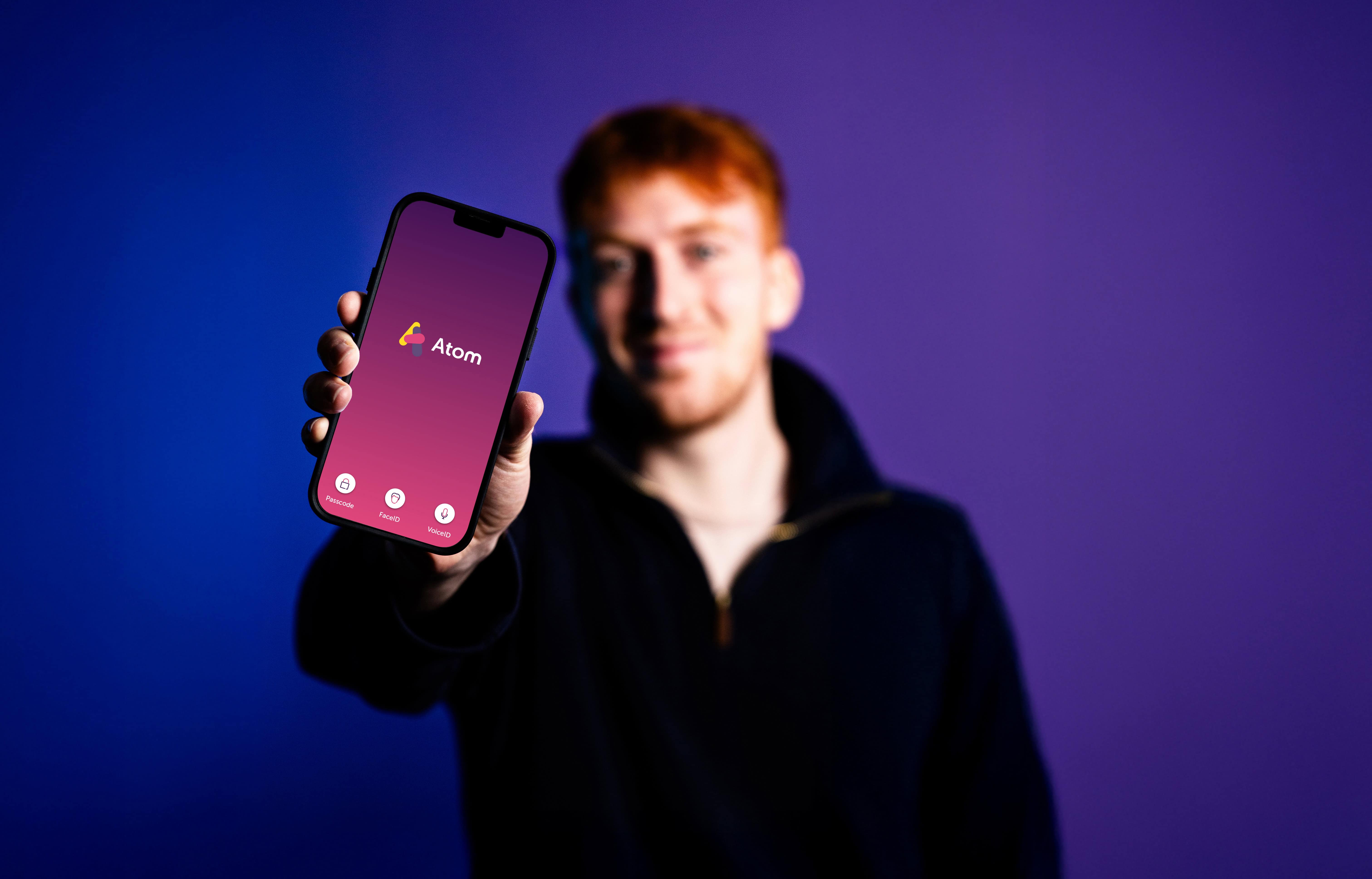 A man holding a phone with the Atom Bank app on display