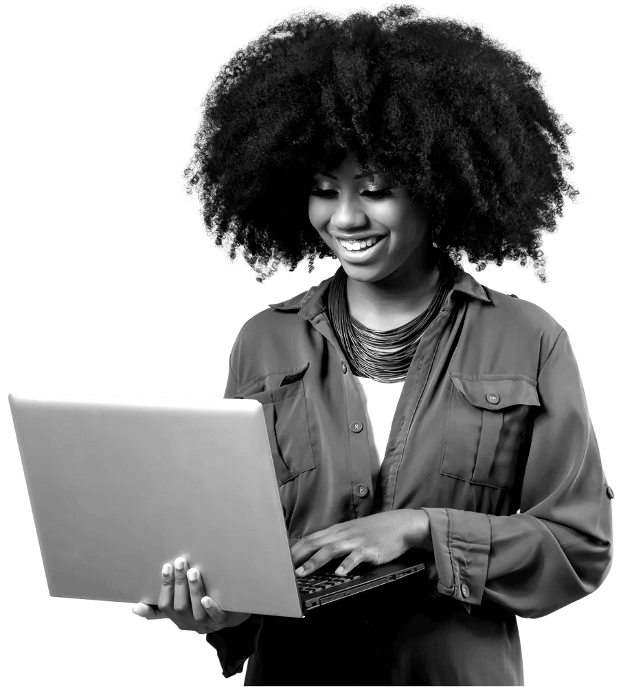 A woman standing and smiling whilst typing on her laptop