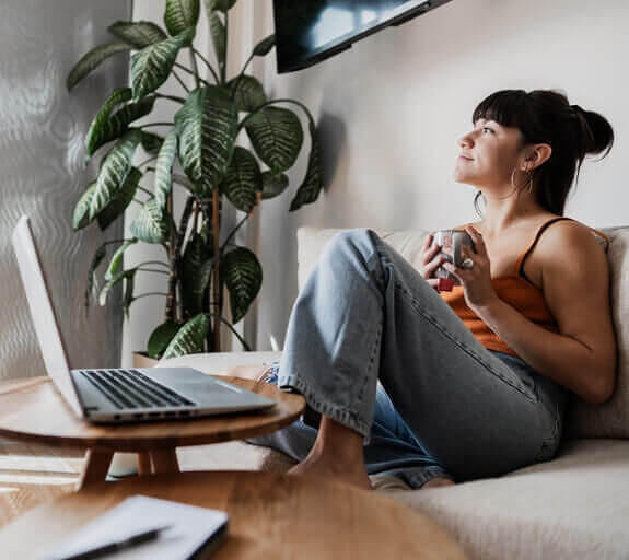 Young man wearing glasses with a beard meditating whilst sat infront of a laptop