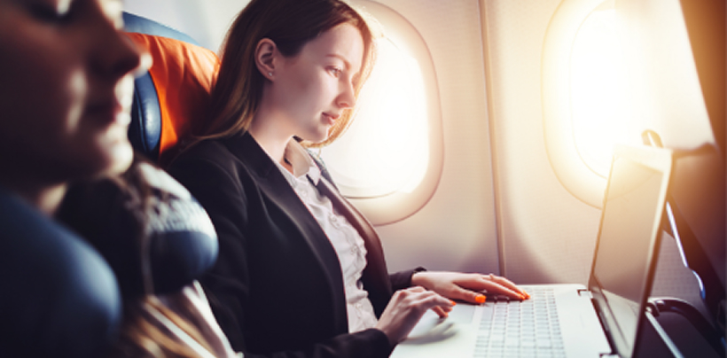 A woman is sat on a plane working on her laptop