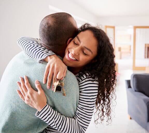 A couple sharing an embrace while one of them is holding a set of house keys