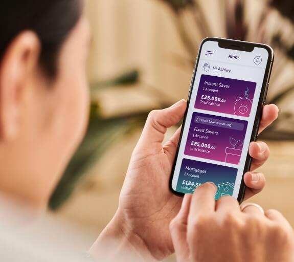 Someone holding a phone looking at the atom bank app products page